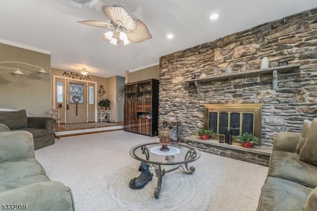 carpeted living room featuring ceiling fan and a stone fireplace