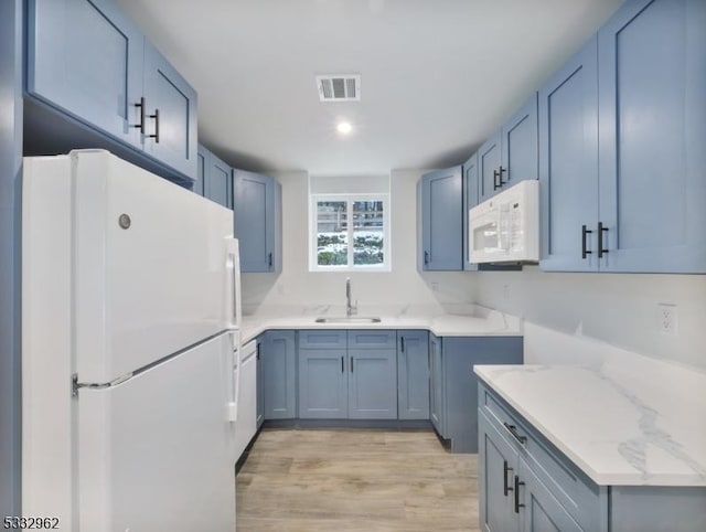 kitchen featuring white appliances, light hardwood / wood-style floors, light stone counters, and sink