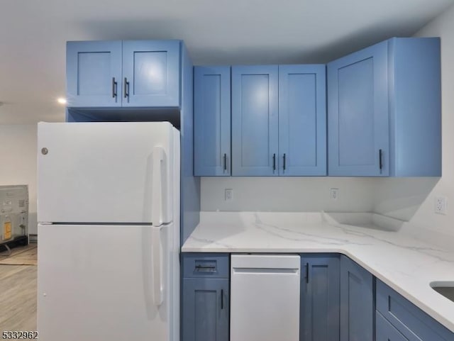 kitchen featuring blue cabinetry, white fridge, and light stone countertops