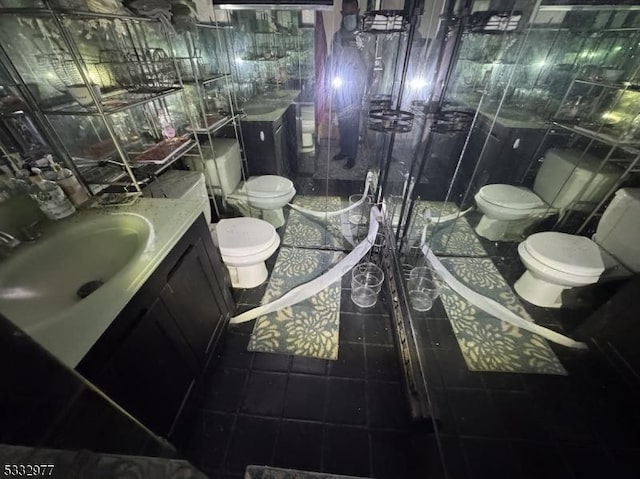 bathroom with toilet, vanity, tile patterned flooring, and tile walls