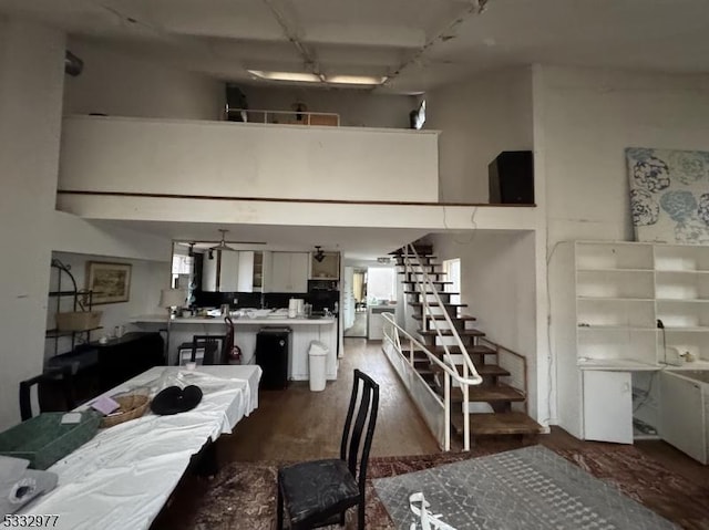 dining room featuring a towering ceiling, ceiling fan, and wood-type flooring