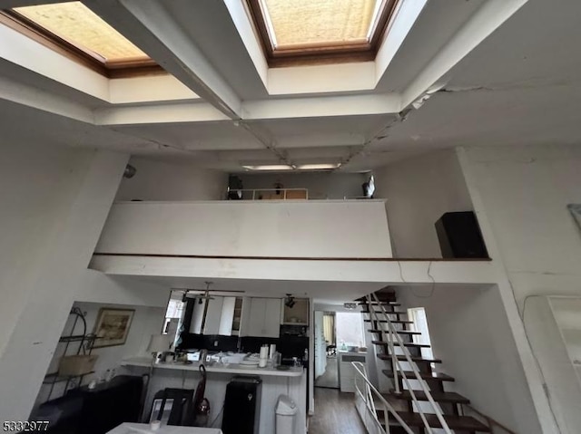 kitchen featuring a high ceiling, a skylight, hardwood / wood-style floors, and white cabinetry