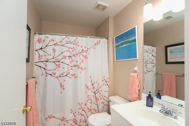 bathroom featuring toilet, vanity, and curtained shower