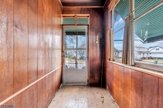 doorway to outside with wood walls