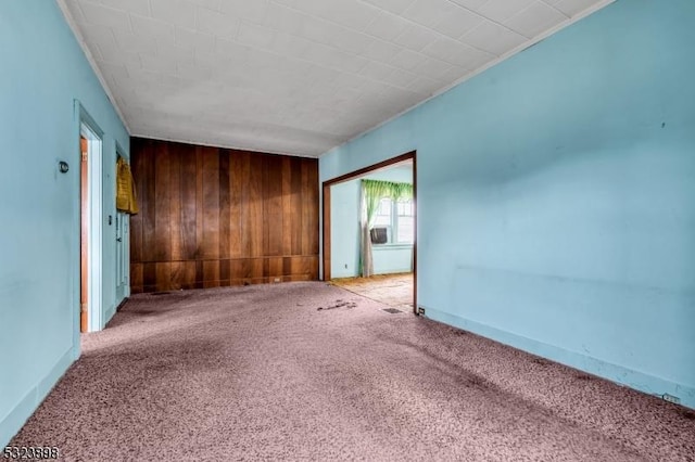 unfurnished room with carpet floors and wood walls