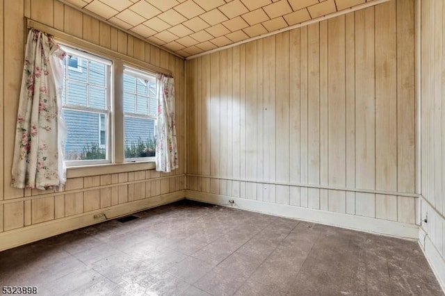 unfurnished room with plenty of natural light and wood walls