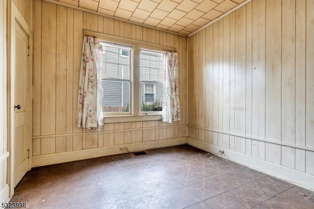 unfurnished room featuring wood walls