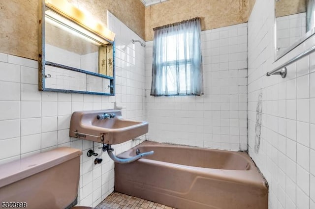 bathroom featuring toilet, a tub to relax in, tile patterned flooring, tile walls, and sink