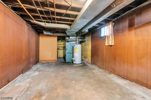 basement featuring heating unit, water heater, and wooden walls