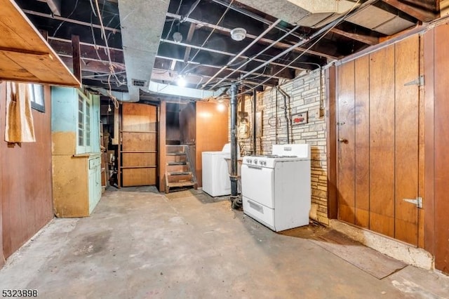 basement featuring wood walls and washing machine and clothes dryer