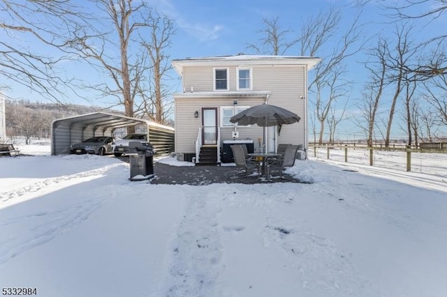 snow covered back of property with a carport