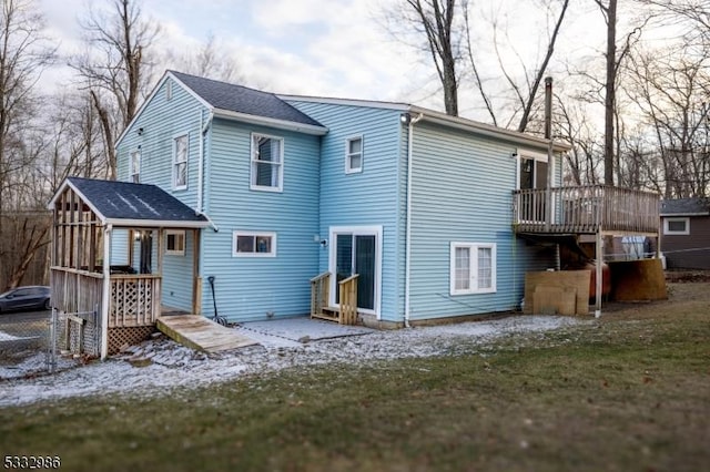 snow covered rear of property featuring a sunroom and a wooden deck