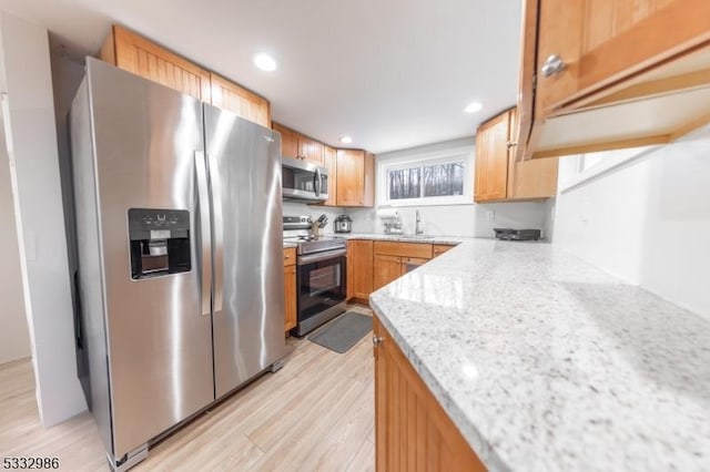 kitchen with sink, light hardwood / wood-style flooring, light stone countertops, and stainless steel appliances