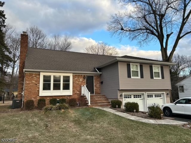 view of front of property featuring a garage, a front yard, and central AC