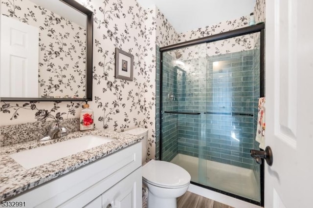 bathroom with wood-type flooring, toilet, a shower with shower door, and vanity