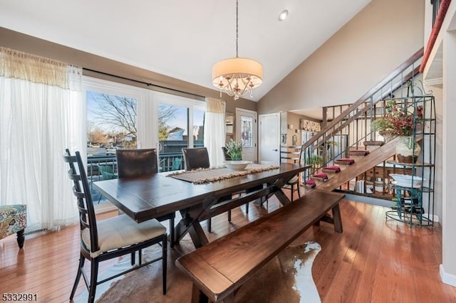 dining room featuring hardwood / wood-style flooring, a chandelier, and vaulted ceiling