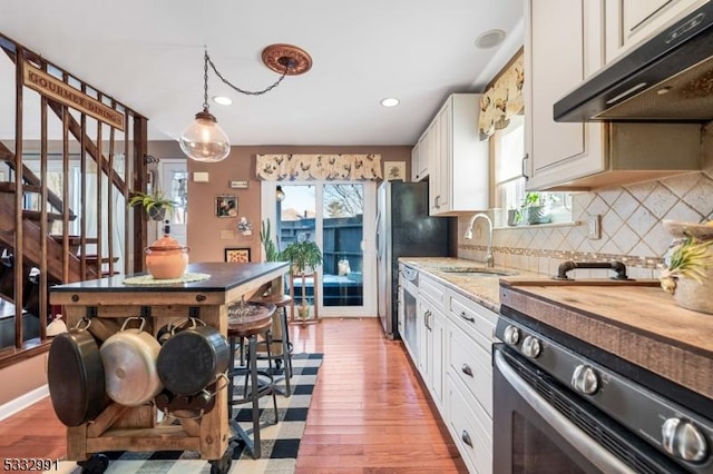 kitchen featuring sink, decorative light fixtures, white cabinetry, tasteful backsplash, and light hardwood / wood-style floors