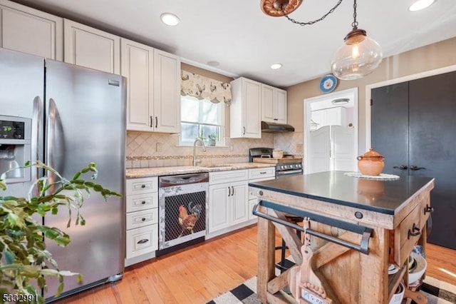 kitchen with appliances with stainless steel finishes, hanging light fixtures, white cabinets, sink, and backsplash