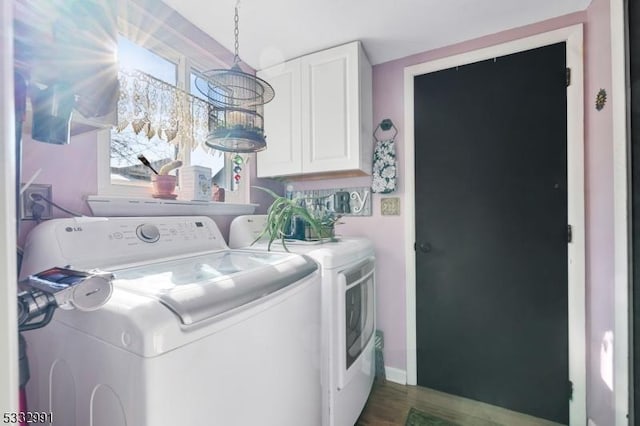 clothes washing area featuring cabinets and washer and clothes dryer