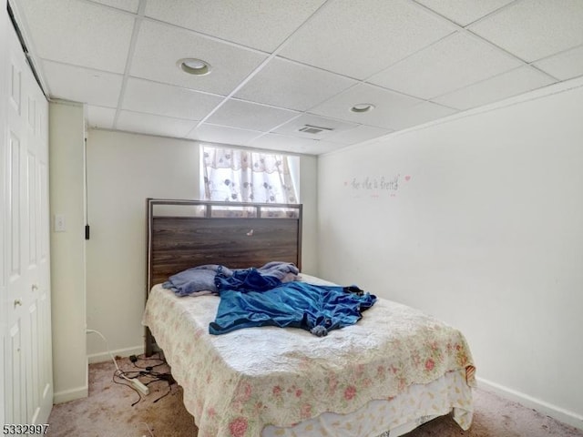 bedroom with a closet, carpet, and a drop ceiling