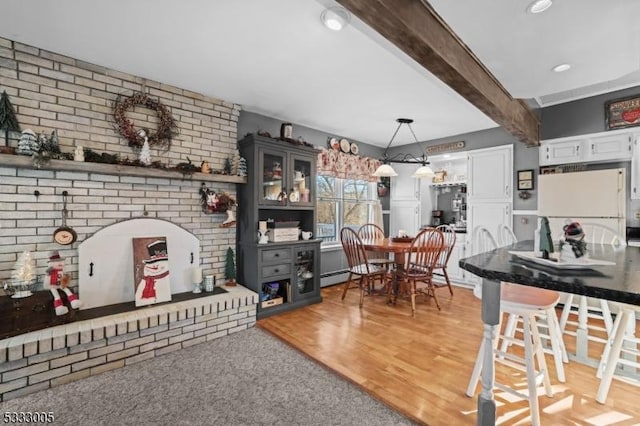 interior space featuring white refrigerator, hanging light fixtures, hardwood / wood-style flooring, a breakfast bar, and beam ceiling