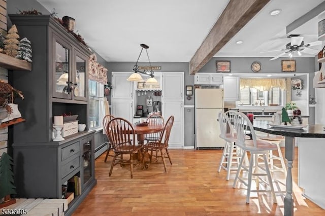 dining room featuring ceiling fan, a baseboard heating unit, light hardwood / wood-style floors, beam ceiling, and sink