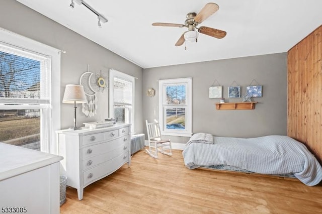 bedroom featuring radiator, ceiling fan, track lighting, and light hardwood / wood-style floors