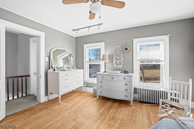 bedroom with ceiling fan, rail lighting, light hardwood / wood-style flooring, and radiator