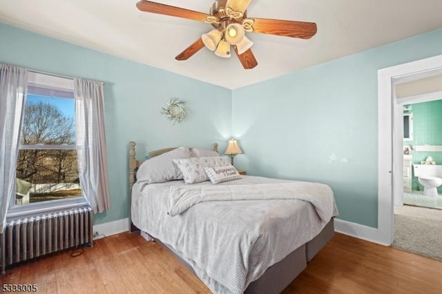 bedroom featuring ceiling fan, radiator heating unit, and hardwood / wood-style flooring