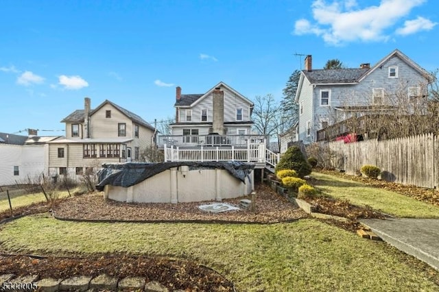 rear view of house with a lawn and a swimming pool side deck