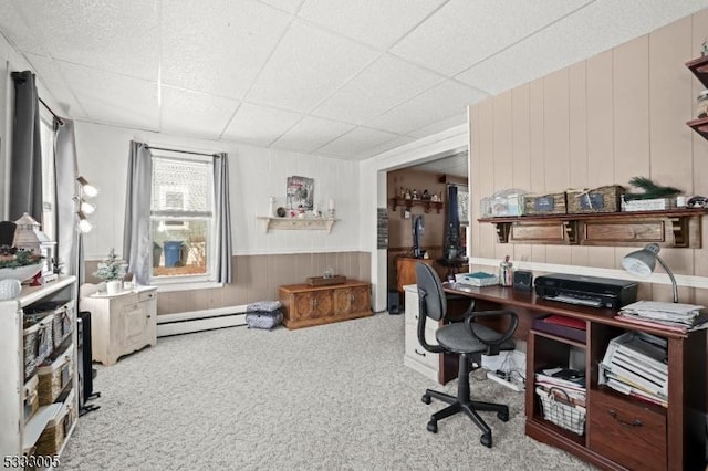 carpeted office with a baseboard heating unit, a paneled ceiling, and wooden walls