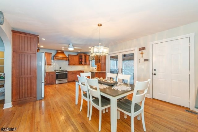 dining space with light wood-type flooring and ceiling fan with notable chandelier