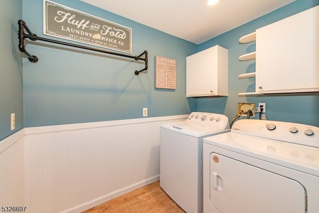 washroom with cabinets, light hardwood / wood-style floors, and washer and clothes dryer