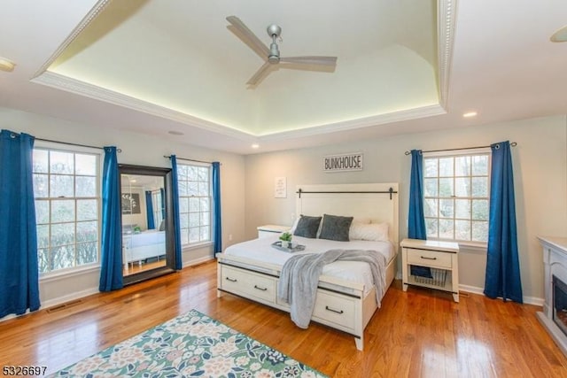 bedroom featuring ceiling fan, a tray ceiling, and light hardwood / wood-style floors