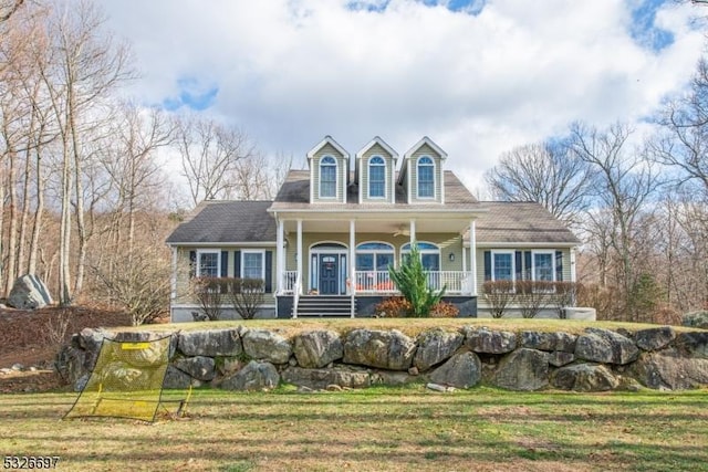 new england style home featuring covered porch and a front yard