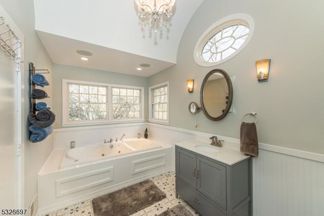 bathroom featuring tile patterned flooring, vanity, a notable chandelier, vaulted ceiling, and a washtub