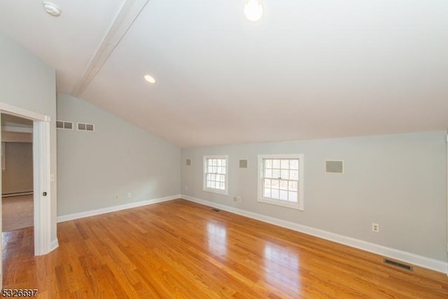 additional living space with vaulted ceiling with beams, a baseboard radiator, and light hardwood / wood-style flooring