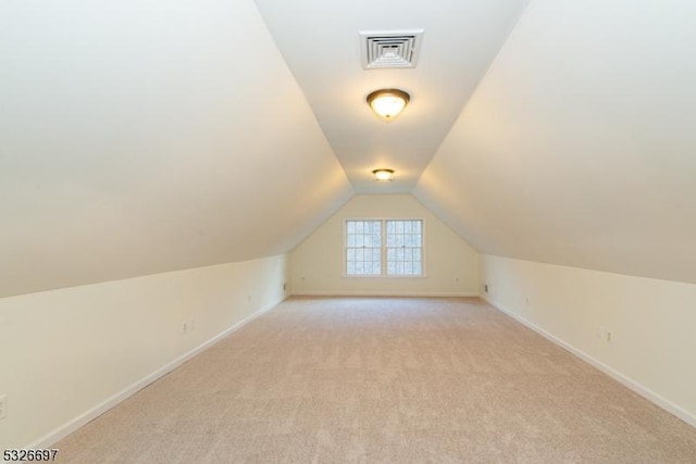 bonus room with vaulted ceiling and light colored carpet