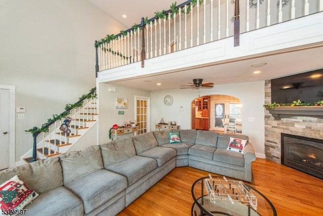 living room featuring ceiling fan, a high ceiling, wood-type flooring, and a fireplace