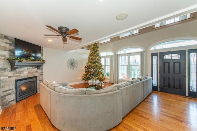 living room featuring ceiling fan, a fireplace, and light hardwood / wood-style flooring