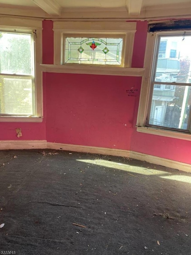 empty room featuring beamed ceiling and crown molding