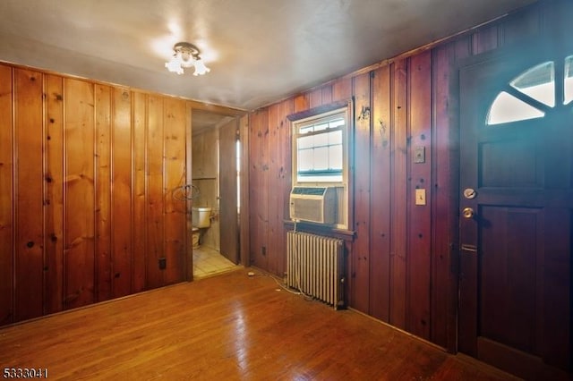 foyer featuring wood walls, light hardwood / wood-style floors, and radiator