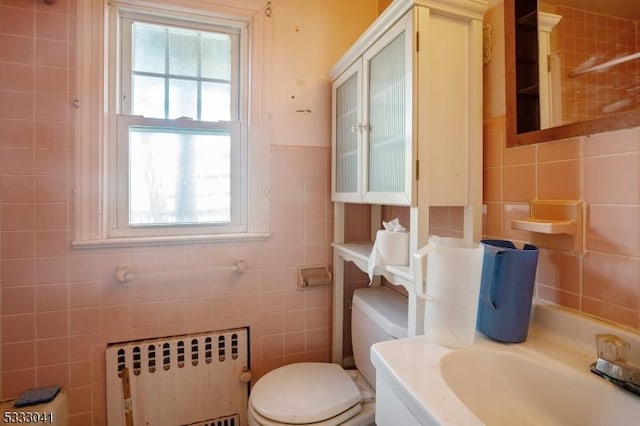 bathroom with tile walls, toilet, vanity, and radiator heating unit