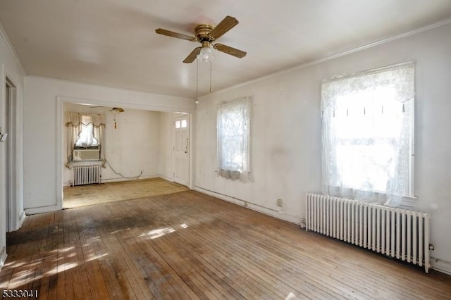 unfurnished room featuring ceiling fan, hardwood / wood-style floors, radiator heating unit, and crown molding