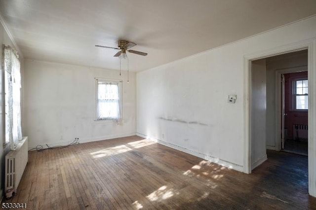 spare room with ceiling fan, a healthy amount of sunlight, dark hardwood / wood-style floors, and radiator