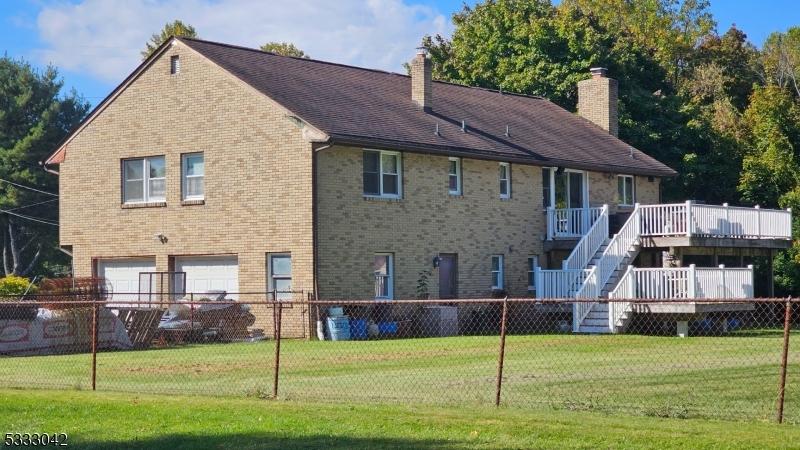 back of property with a garage, a deck, and a lawn