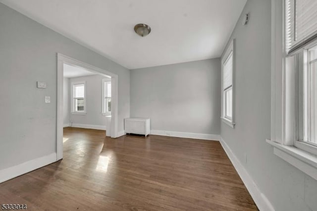 unfurnished room with dark hardwood / wood-style floors, plenty of natural light, and radiator heating unit