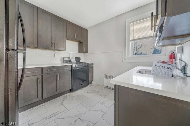 kitchen with radiator, dark brown cabinetry, gas range, and black refrigerator