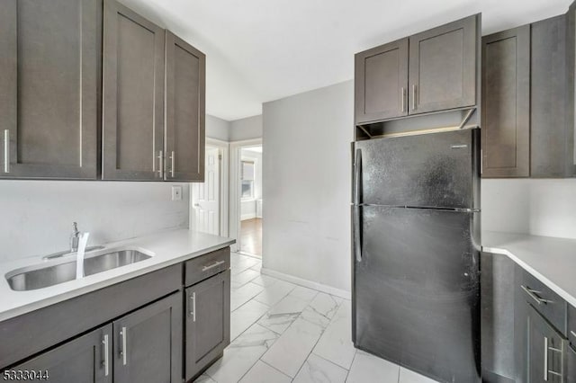 kitchen with black refrigerator, dark brown cabinets, and sink