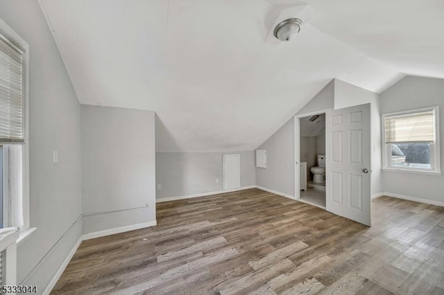 additional living space with hardwood / wood-style flooring and vaulted ceiling